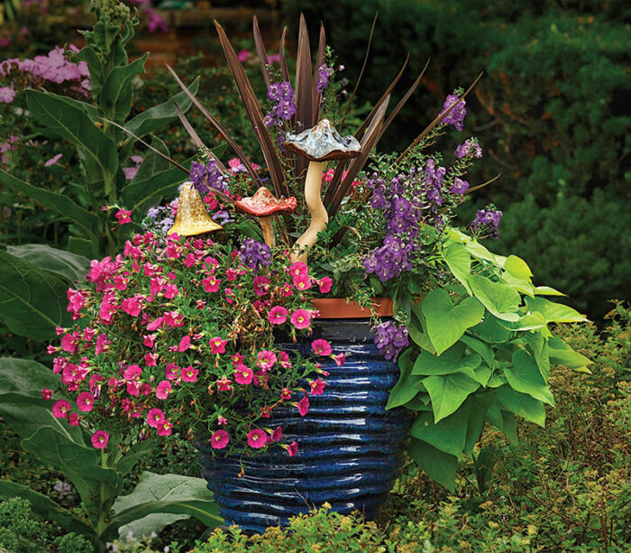 container with bright flowers and foliage with ceramic mushrooms