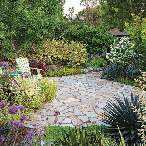 small stone patio in garden with Adirondack chairs