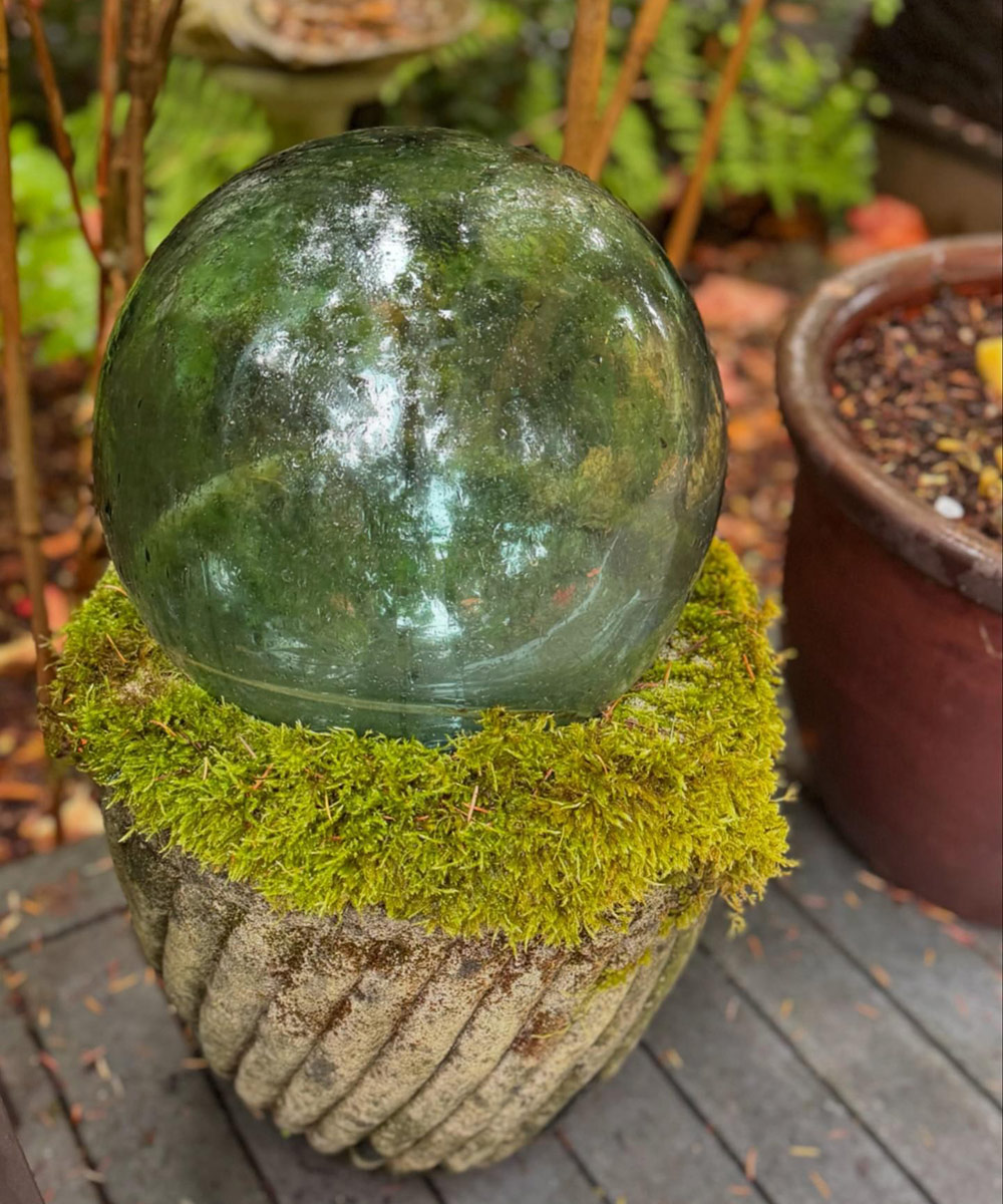 green glass orb in a pot with moss