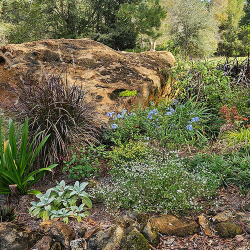 round garden bed with large boulder in the center