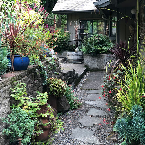 stepping stone path leading to patio with container plantings all around