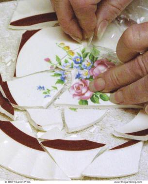 hand showing shattered china dish that had packing tape on it to keep it together